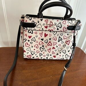 Kate Spade heart cross body bag. Beige background with red & black hearts.